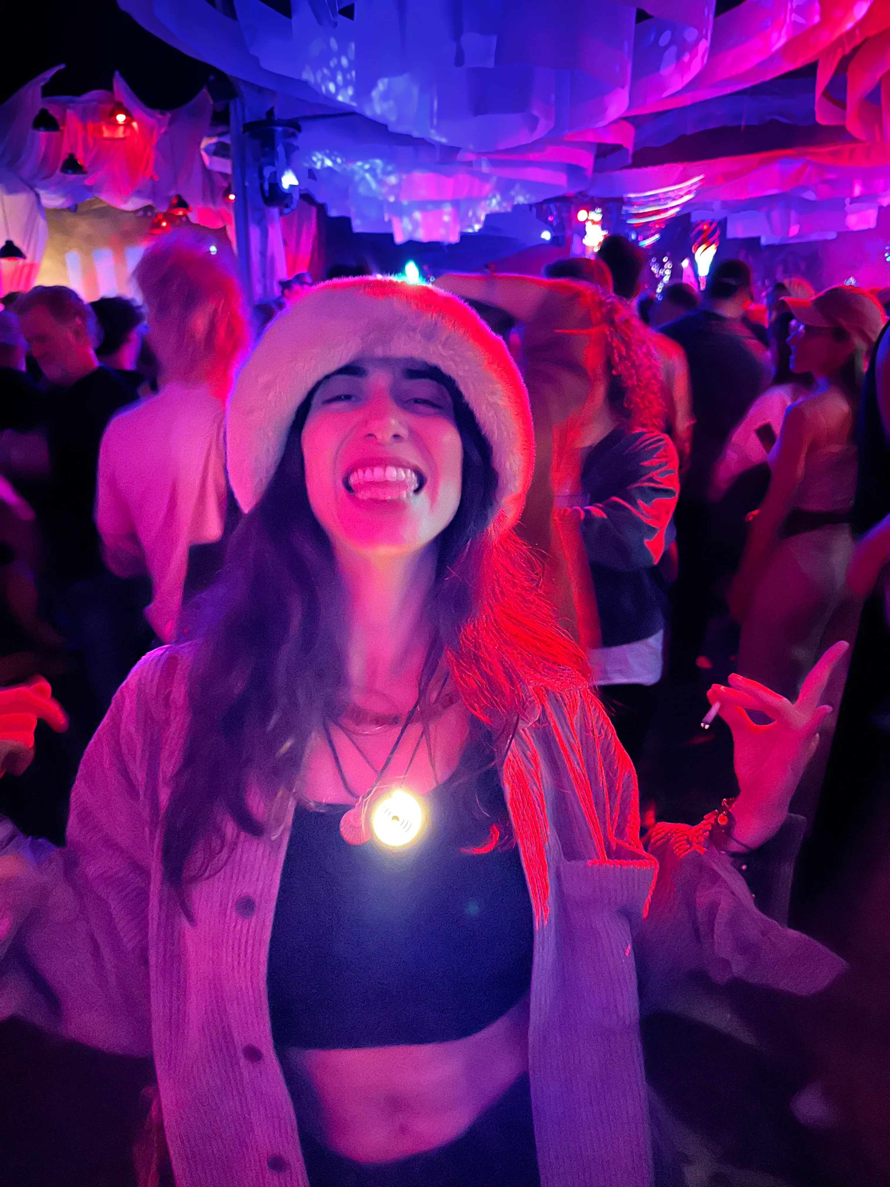 Woman dancing at a colorful night event while wearing a glowing Spirluma necklace