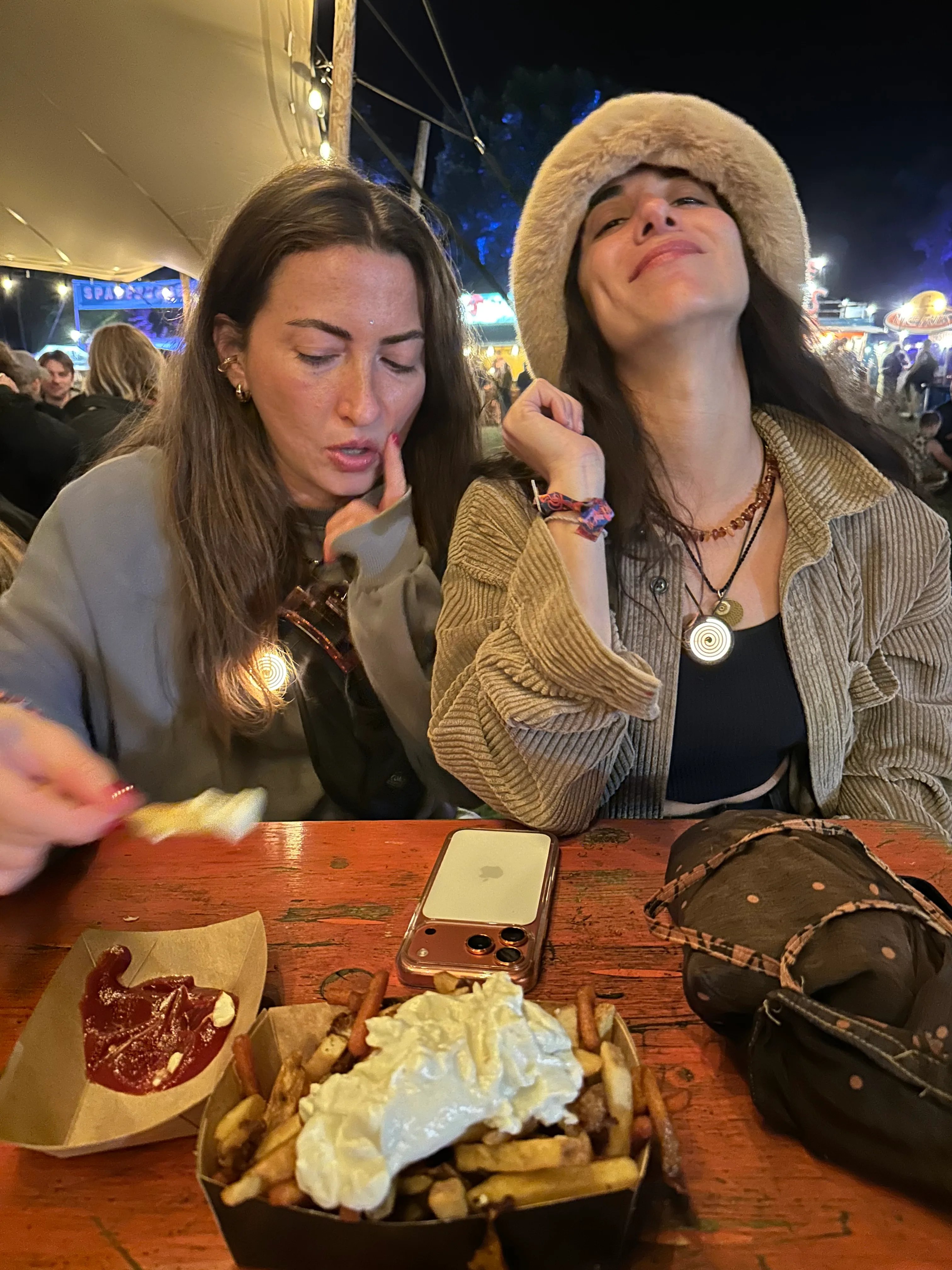 Two friends wearing glowing Spirluma necklaces at a night market