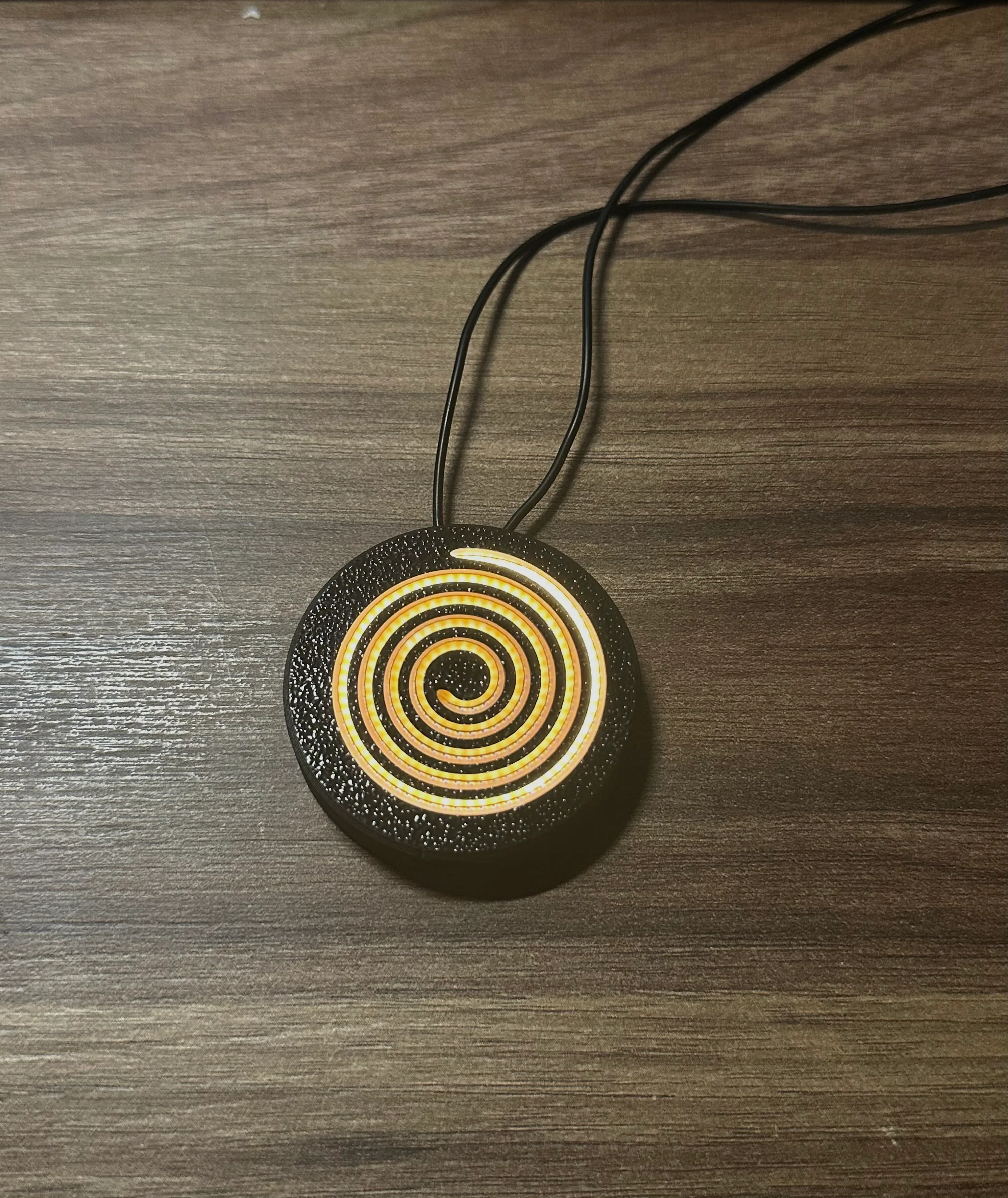 Spirluma's glowing spiral pendant on a dark surface